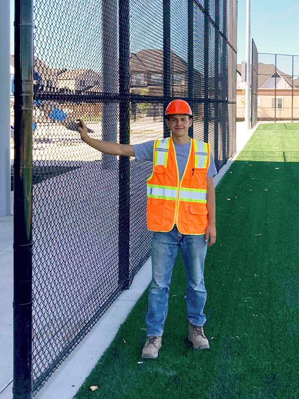 Ariel Sima setting a fence post on a job site