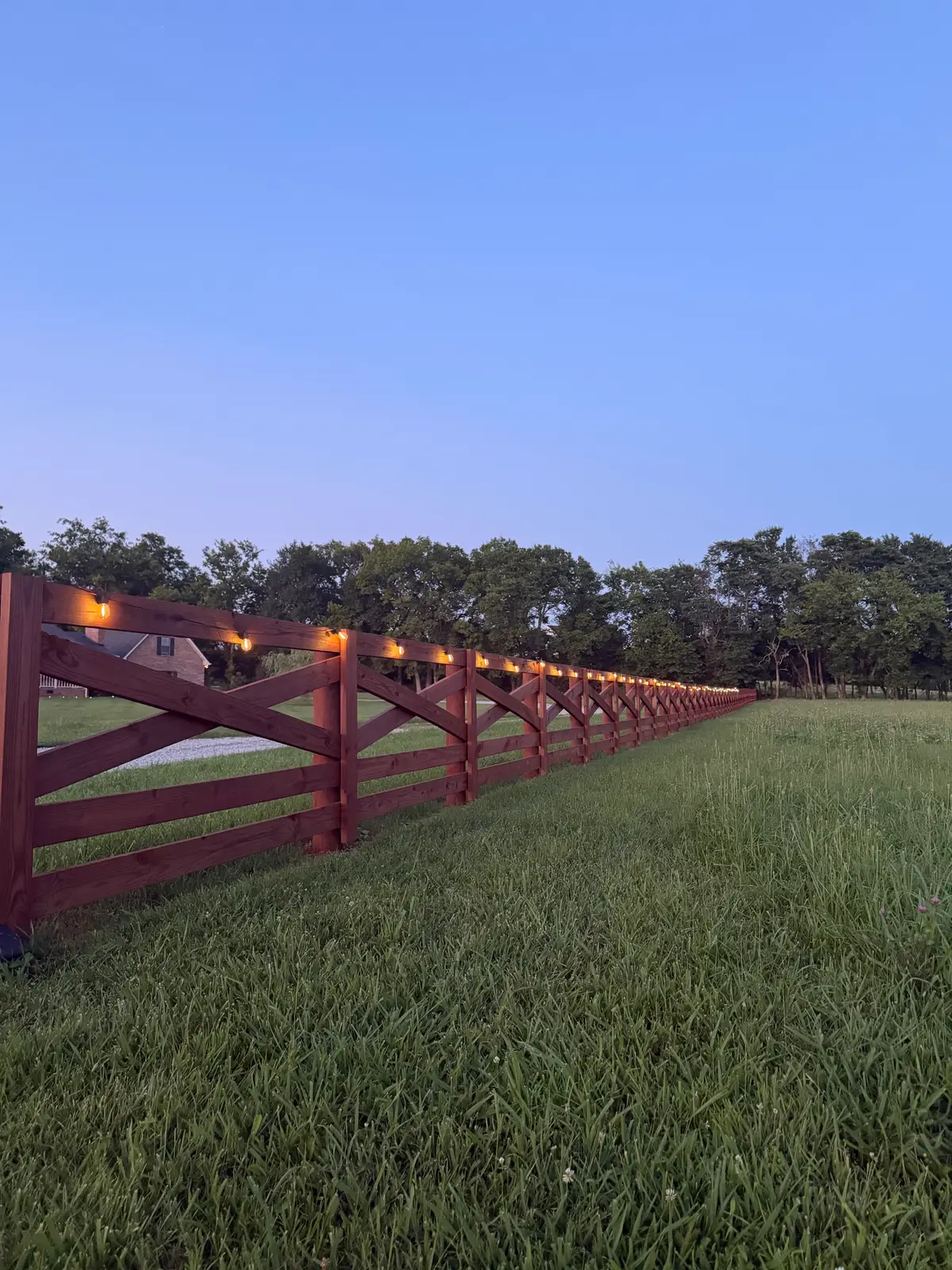 Burgundy ranch fence dusk lighting, installed by Duck Duck Fence